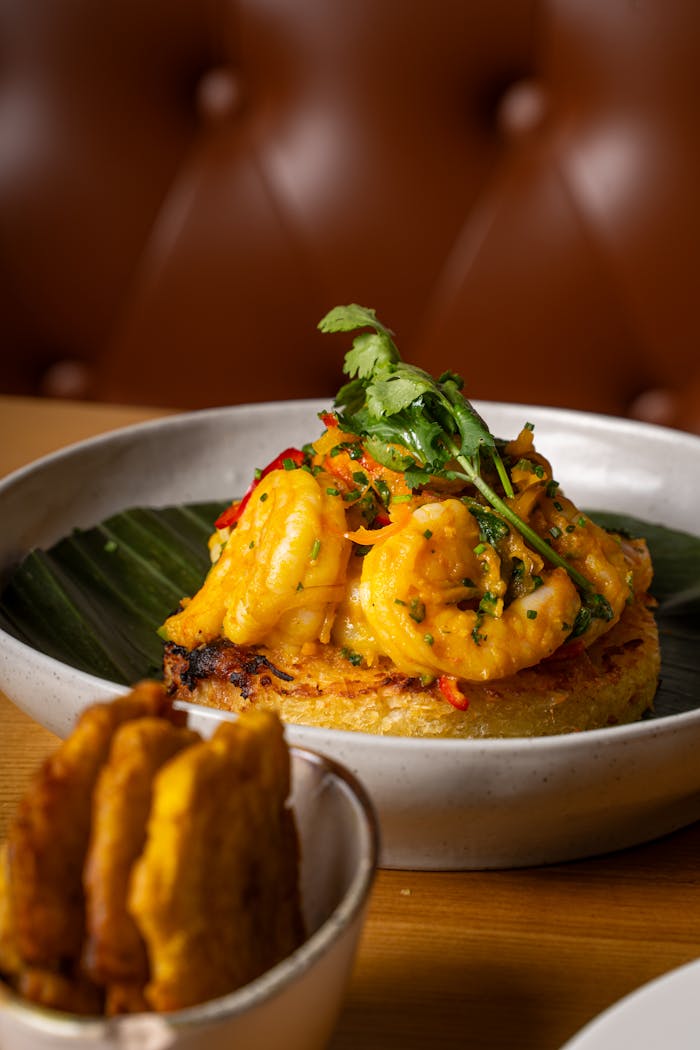 Delicious shrimp plated on a fried base with plantains and garnished with herbs.