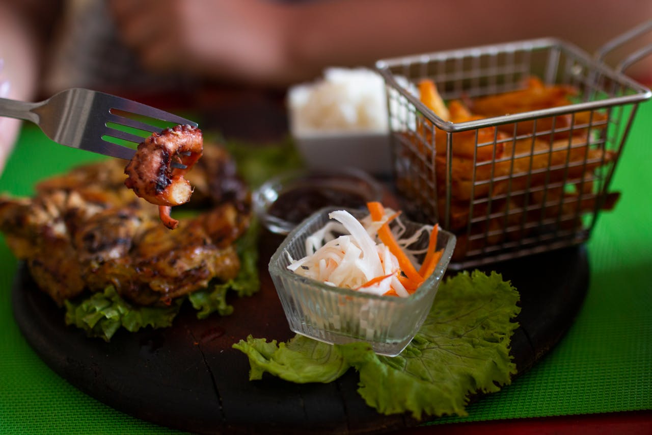 Close-up of grilled seafood dish with salad and fries on a decorative plate.